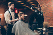© deagreez - Great job! Hairstylist and a client in a barber shop. Red bearded young man got a stunning hairdo and his beard got cutted perfectly. Hairdresser is taking off the cape