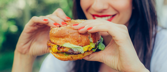 Happy young woman eat tasty fast food burger