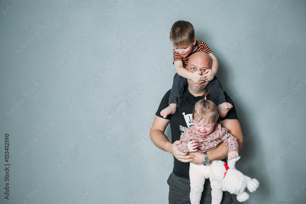 stressed young dad with two small children in his arms - obrazy, fototapety, plakaty 