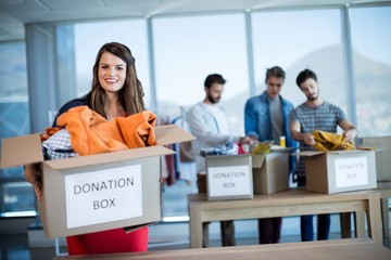 Wall Mural - Smiling woman holding a donation box in office