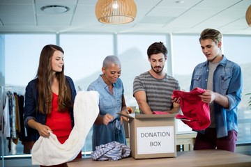 Wall Mural - Creative business team sorting clothes in donation box