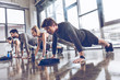 © LIGHTFIELD STUDIOS - group of athletic young people in sportswear doing push ups or plank at the gym, group fitness concept