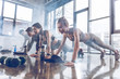 © LIGHTFIELD STUDIOS - group of athletic young people in sportswear doing push ups or plank at the gym, group fitness concept