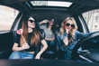 © F8  \ Suport Ukraine - Three beautiful young cheerful women looking at each other with smile and eating lollipops while sitting in car