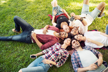 Group of young people laying on the grass in circle, happy, smiling