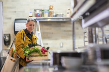 Female Chef With Crate Of Vegetables Standing At Kitchen Counter In Restaurant