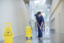Male Worker Cleaning Floor At Hospital Corridor