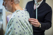 © Cavan Images - Midsection of male doctor listening to patient's breathing in hospital ward