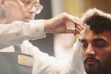Barber Cutting Man's Hair In Salon