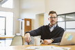 © Cavan Images - Portrait of businessman with laptop computer and coffee cup sitting at desk in office