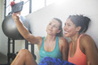 © Cavan Images - Happy female friends taking selfie through mobile phone in health club