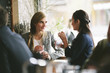 © Cavan Images - Female friends talking while having drinks by window in restaurant