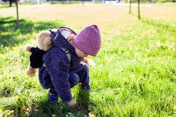 Little girl on the grass in the park, sunny spring day