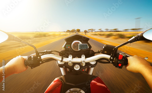 Biker driving a motorcycle rides along the country road , morning scene Fototapeta