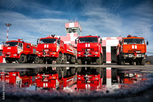 Cuadros en Lienzo Airfield fire trucks with reflection in a puddle near garage boxes