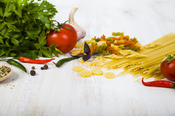 Raw pasta and spices in wooden table.