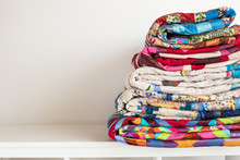 Sewing And Fashion Concept - Stack Of Colorful Quilts, Beautiful Bedspreads Stacked In Several Rows In Height For Storage, Sale Patchwork Productions On A White Background, Copy Space