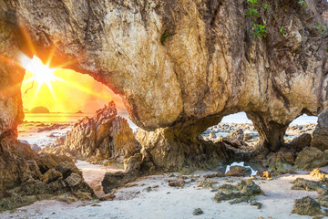 Wall Mural - sunlight of passed tunnel rock on the beach at sunset