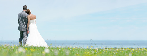 Bride and groom standing together in front of the sea