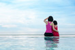 © Prasit Rodphan - Asian mother with daughter sitting on the edge of pool and stare at the sea in Phuket, Thailand. Summer, Vacation and travel concept