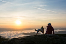 Girl And Her Dog Looking At Something On A High Peak.