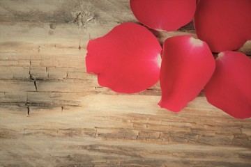 red petals from a rose on old wooden table, romantic and top view