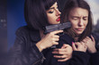 Beautiful brunette sexy spy agent (killer or police) woman in leather jacket and jeans with a gun in her hand catch a girl on parking