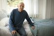 © Erickson Stock - Portrait of a concerned senior man sitting on a bed in his bedroom.