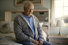 Thoughtful Man Sitting On Bed At Home