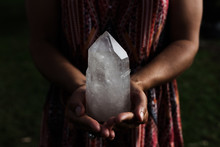 A Young Woman Holding A Large, Luminous Quartz Crystal Appears Powerful In Dramatic Lighting.