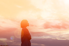 Silhouette Of Woman Praying Over Beautiful Sky Background