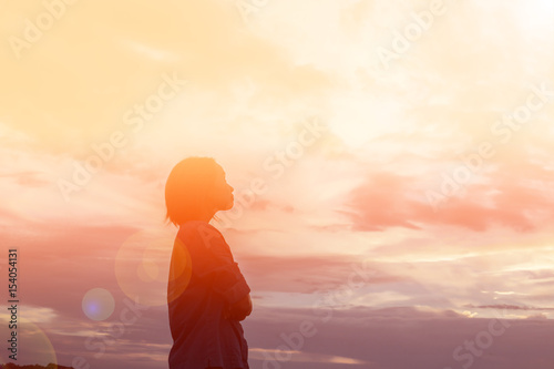 Cuadros en Lienzo Silhouette of woman praying over beautiful sky background