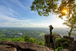 © yotrakbutda - Photographer is taking a picture of view of natural scenery on rock.