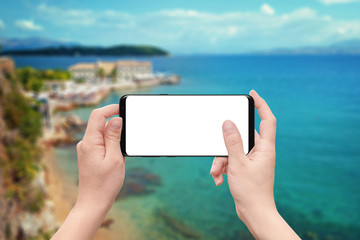 Poster - Woman play game or use app on mobile phone with isolated white screen. Coast and sea in background.