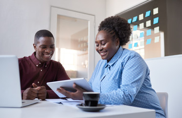 Two young African office colleagues working with a tablet