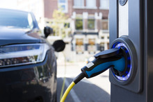 View Of An Electric Car Charging Column And In The Background A Partial View Of A Car