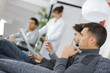 © auremar - Men in waiting room, one looking at phone, the other reading a magazine