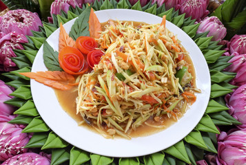 papaya salad is in a white plate with a banana leaf