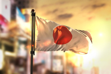Canvas Print - Japan Flag Against City Blurred Background At Sunrise Backlight