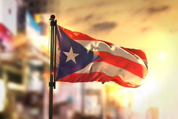 Wall Mural - Puerto Rico Flag Against City Blurred Background At Sunrise Backlight