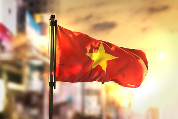 Sticker - Vietnam Flag Against City Blurred Background At Sunrise Backlight
