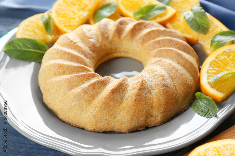 Plate with appetizing citrus cake and orange slices, close up