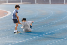 Boy Help Each Other On Blue Track After Fall