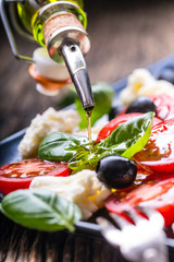 Wall Mural - Caprese Salad.Mediterranean salad. Mozzarella cherry tomatoes basil and olive oil on old oak table. Italian cuisine.