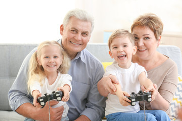 Wall Mural - Grandparents and grandchildren playing video game together at home