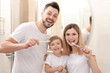 © Africa Studio - Young couple and their beautiful son brushing teeth near mirror in bathroom