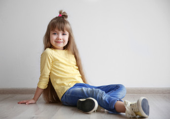 Wall Mural - Little fashion girl sitting on floor in light room