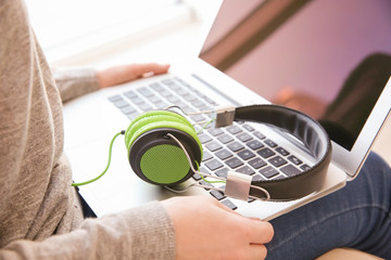 Canvas Print - Audio book concept. Young woman using laptop with headphones, close up