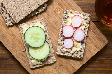 Canvas Print - Wholemeal rye crispbread with brie cheese, radish and cucumber slices, photographed overhead with natural light