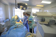 Leinwandbild Motiv Syringe pomp with transparent drug in foreground of surgery with two surgeons and nurse